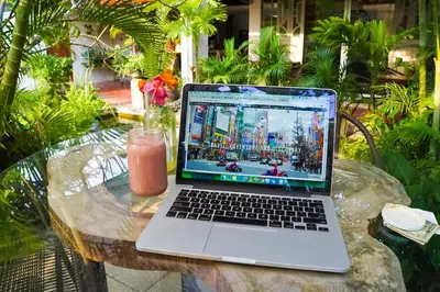 a laptop computer sitting on a table with a drink at Cinco Hotel B&B in San Salvador