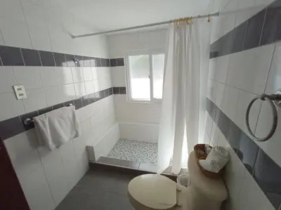 a white bathroom with a shower and a toilet at Cinco Hotel B&B in San Salvador