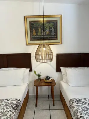 two beds in a room with a table between them at Cinco Hotel B&B in San Salvador