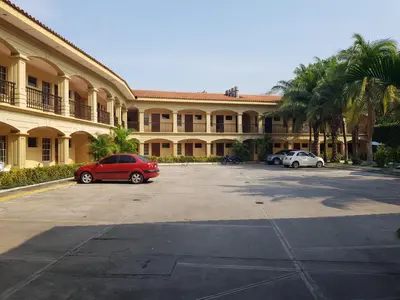 a red car parked in a parking lot in front of a building at Hotel Florencia in San Miguel