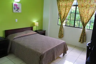 a bedroom with a bed and two windows at Hostal de Asturias in San Salvador