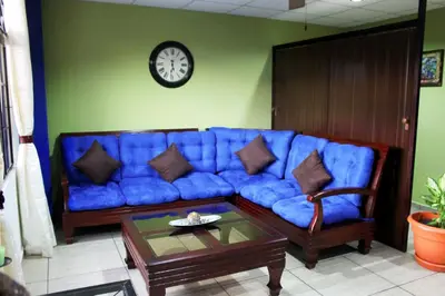 a blue couch in a living room with a clock on the wall at Hostal de Asturias in San Salvador