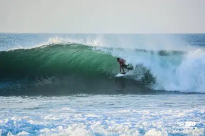 a man riding a wave on a surfboard in the ocean at Puro Surf Hotel & Performance Academy in El Zonte