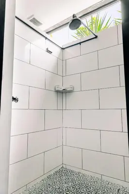 a shower with white tile and a window at Puro Surf Hotel & Performance Academy in El Zonte