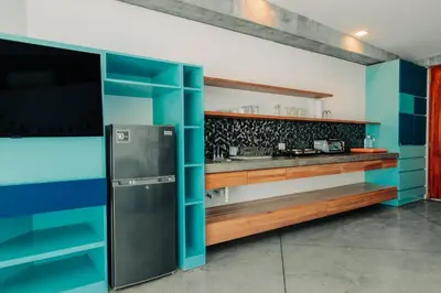 a kitchen with blue walls and a refrigerator at Puro Surf Hotel & Performance Academy in El Zonte