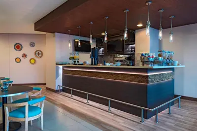 a bar in a restaurant with blue chairs and a counter at Fairfield by Marriott San Salvador in San Salvador