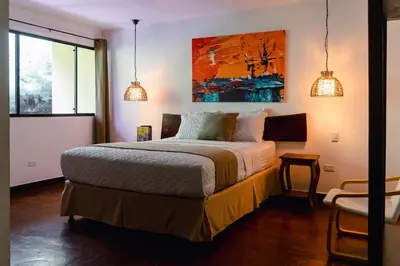 a bedroom with a bed and a painting on the wall at Hotel Juayua in Juayúa