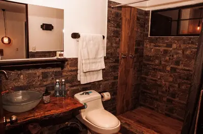 a bathroom with a toilet and a sink and a mirror at Hotel Juayua in Juayúa