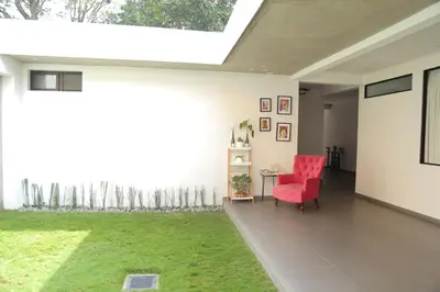 a living room with a red chair and a green yard at Kaleo Hotel Boutique in San Salvador