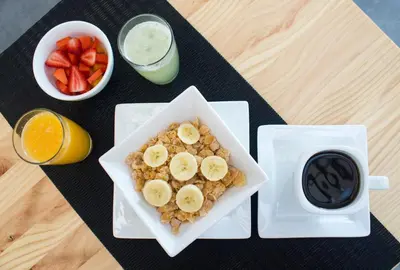 a plate of cereal with bananas and fruit and a cup of coffee at Kaleo Hotel Boutique in San Salvador