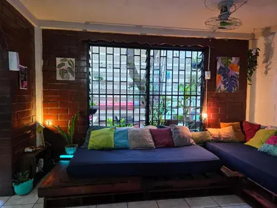 a couch with colorful pillows sitting in front of a window at Pool House Hostel in Santa Ana