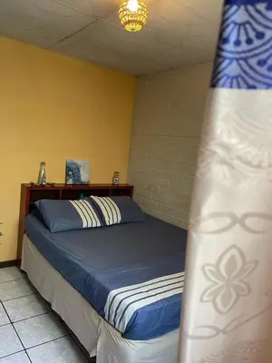 a bedroom with a bed with blue and white sheets at Pool House Hostel in Santa Ana