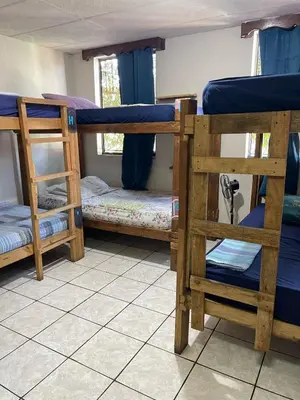 a room with three bunk beds in a room at Pool House Hostel in Santa Ana