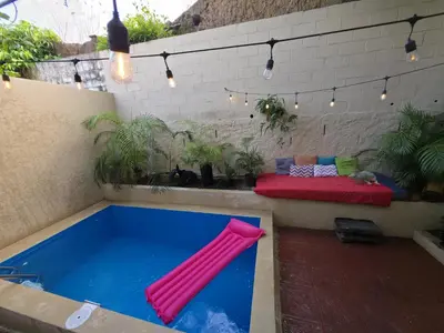 a swimming pool with a red inflatable raft in a backyard at Pool House Hostel in Santa Ana