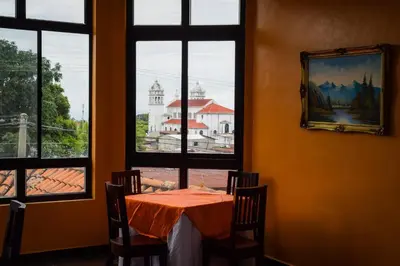 a table with chairs in a room with a window at Vista Los Volcanes Hotel y Restaurante in Juayúa