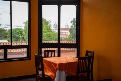 a table with chairs in a room with windows at Vista Los Volcanes Hotel y Restaurante in Juayúa
