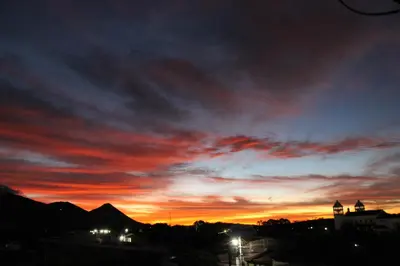 a sunset over a city with a red sky at Vista Los Volcanes Hotel y Restaurante in Juayúa