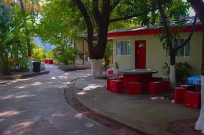 a building with a table and a tree in front of it at Hotel y Restaurante Rincón Familiar in La Libertad