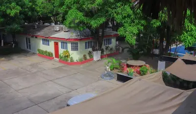 a small white house with a red door at Hotel y Restaurante Rincón Familiar in La Libertad