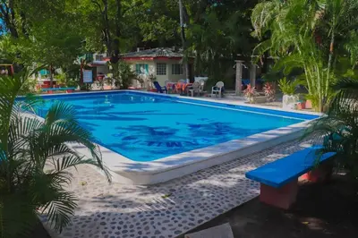 a swimming pool with blue water in a yard at Hotel y Restaurante Rincón Familiar in La Libertad