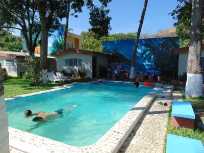 a man swimming in a swimming pool in a yard at Hotel y Restaurante Rincón Familiar in La Libertad