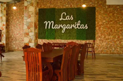 a restaurant with a table and chairs and a sign that says las margaritas at Hotel y Restaurante Las Margaritas in Perquín