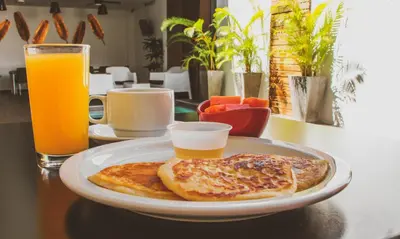 a plate of food with toast and orange juice on a table at Remfort Hotel in Santa Ana
