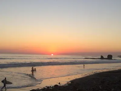 a group of people on the beach at sunset at Hotel & Bar La Guitarra in El Sunzal
