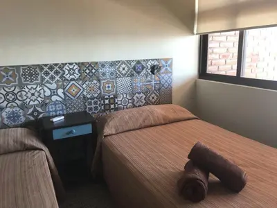 a bedroom with two beds and a tile wall at Hotel & Bar La Guitarra in El Sunzal