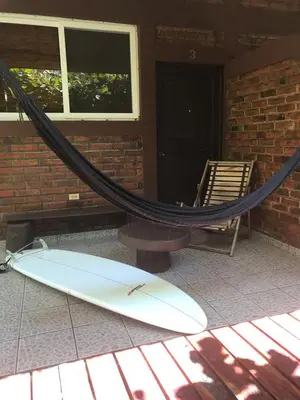a surfboard and a hammock in front of a house at Hotel & Bar La Guitarra in El Sunzal