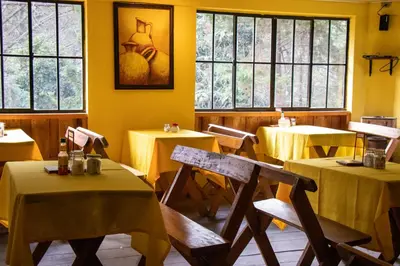 a restaurant with tables and chairs with yellow walls and windows at Alla Arriba in Las Cruces
