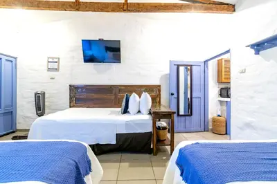 a bedroom with two beds and a tv on the wall at Hotel Casa Pino, Tu Casa en Ataco in Concepción de Ataco