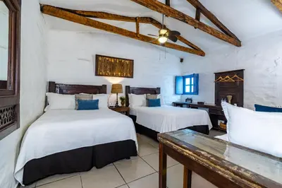 two beds in a room with white walls and wooden beams at Hotel Casa Pino, Tu Casa en Ataco in Concepción de Ataco