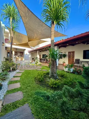 a garden with palm trees and a patio at Hostal DEYLUWIN in Juayúa