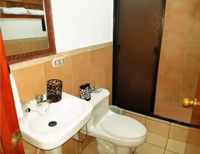 a bathroom with a white toilet and a sink at Hostal Las Puertas in Santa Ana