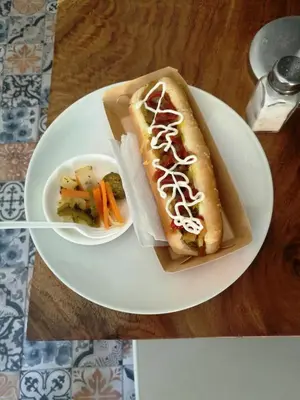 a white plate with a hot dog and a bowl of vegetables at Hotel Boutique Valverde Santa Elena in San Salvador