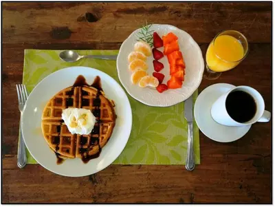 a table with two plates of waffles and a cup of coffee at Hotel Boutique Valverde Santa Elena in San Salvador