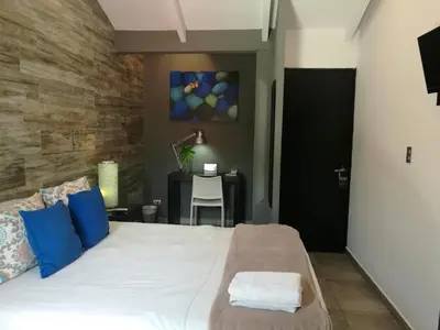 a bedroom with a bed with blue pillows and a table at Hotel Boutique Valverde Santa Elena in San Salvador