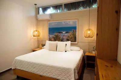 a bedroom with a white bed with a window at Hotel Michanti in El Zonte