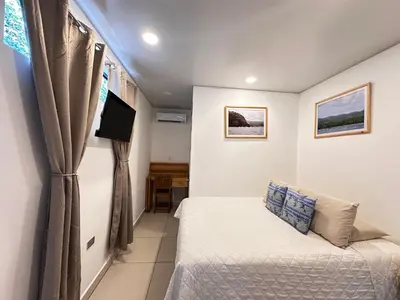 a small bedroom with a bed and a tv at Hotel Michanti in El Zonte