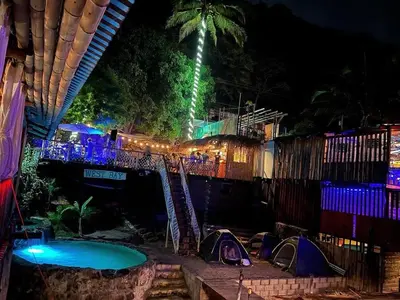 a swimming pool at night with tents and lights at Captain Morgan Hostel Lake Coatepeque in Santa Ana