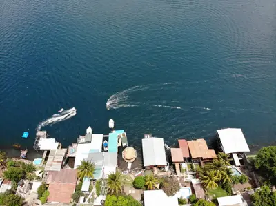 an aerial view of a house and a boat in the water at Captain Morgan Hostel Lake Coatepeque in Santa Ana