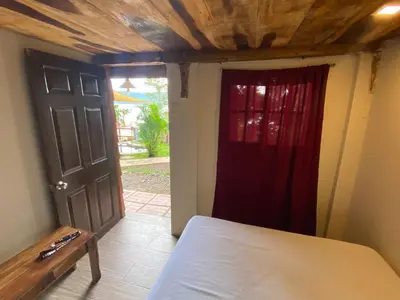 a room with a bed and a door with a red curtain at Captain Morgan Hostel Lake Coatepeque in Santa Ana