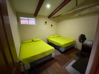 two beds in a small room with green sheets at Captain Morgan Hostel Lake Coatepeque in Santa Ana