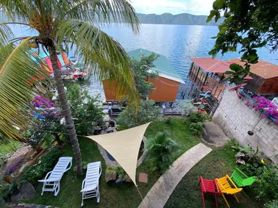 a backyard with chairs and a tent and a palm tree at Captain Morgan Hostel Lake Coatepeque in Santa Ana