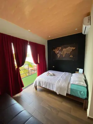 a bedroom with a bed and a window with red curtains at Captain Morgan Hostel Lake Coatepeque in Santa Ana