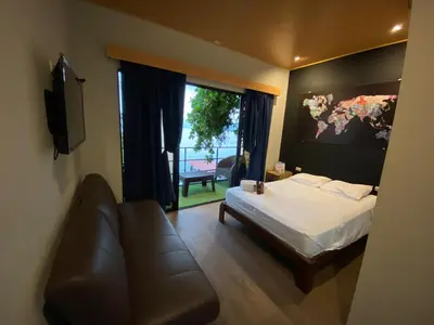 a bedroom with a bed and a couch and a window at Captain Morgan Hostel Lake Coatepeque in Santa Ana