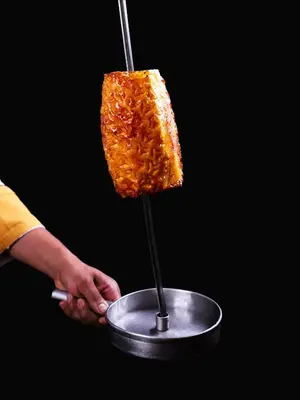 a person holding a piece of food on a stick at Real Intercontinental San Salvador by IHG in San Salvador