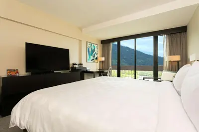 a bedroom with a large white bed and a large window at Hilton San Salvador in San Salvador
