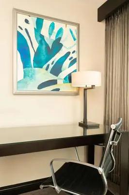 a desk in a hotel room with a lamp and a painting at Hilton San Salvador in San Salvador